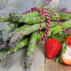 Green asparagus with strawberries on wooden